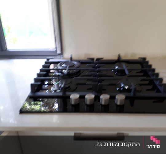 כיריים גז שחורות עם ארבעה מבערים וכפתורים כסופים